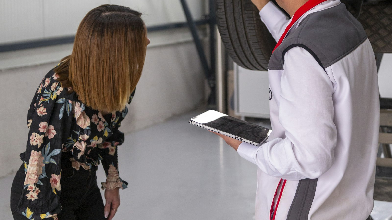 Klant en monteur met tablet bekijken een auto in de werkplaats