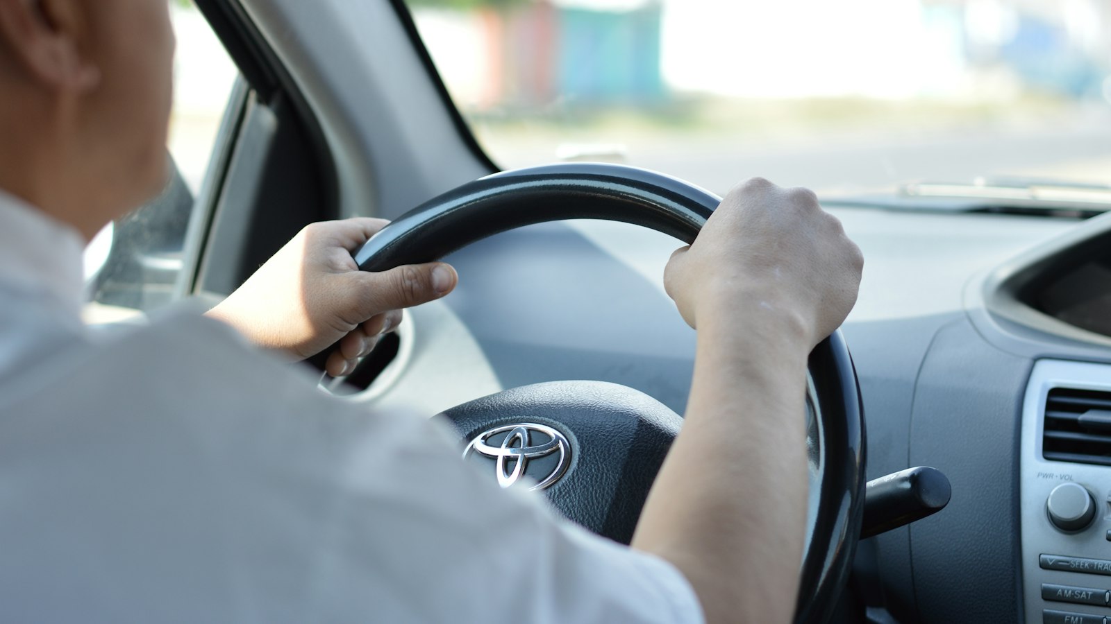 Man achter het stuur van een auto, beide handen aan het stuur