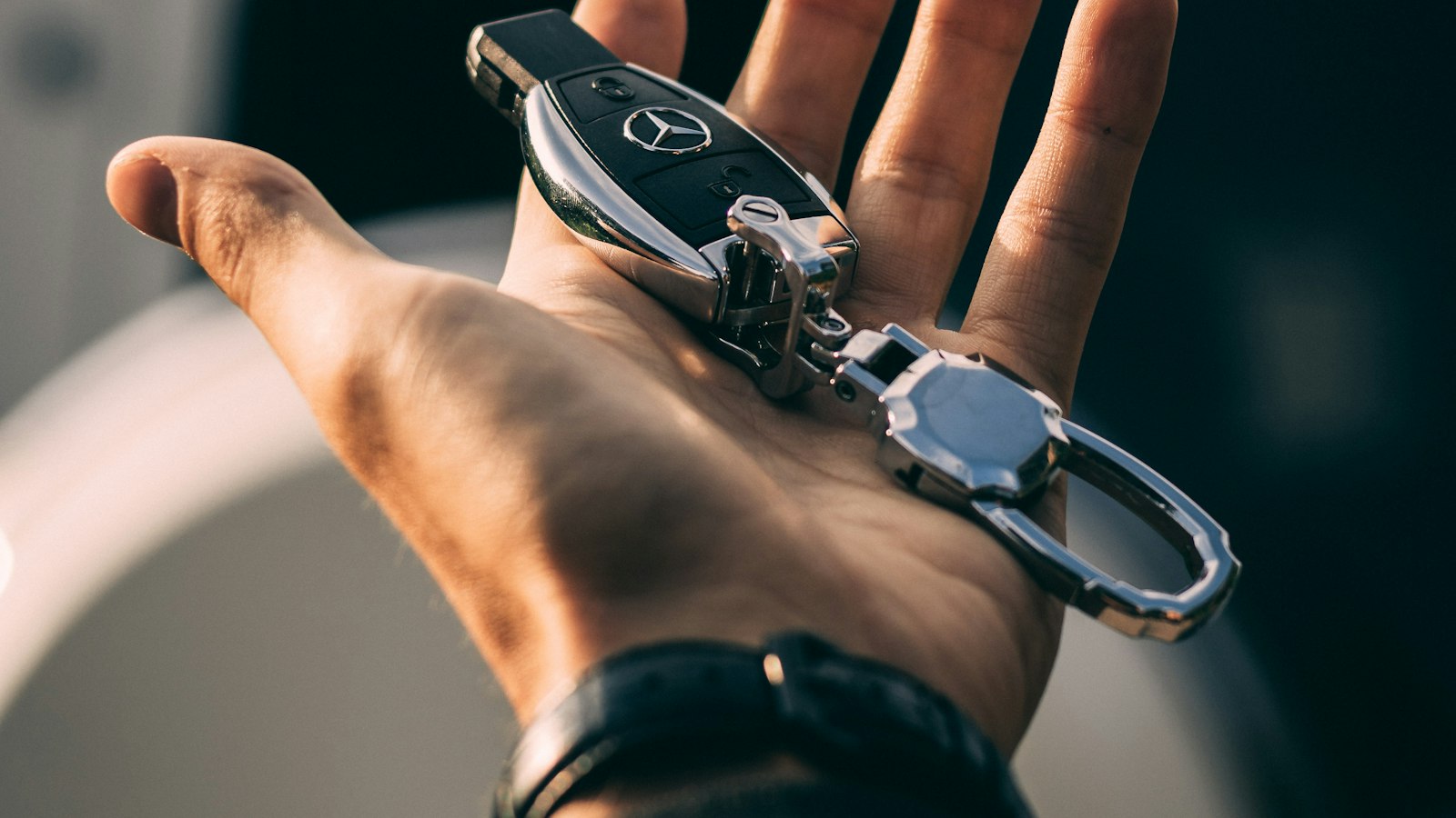 Een hand houdt een autosleutel met sleutelhanger vast