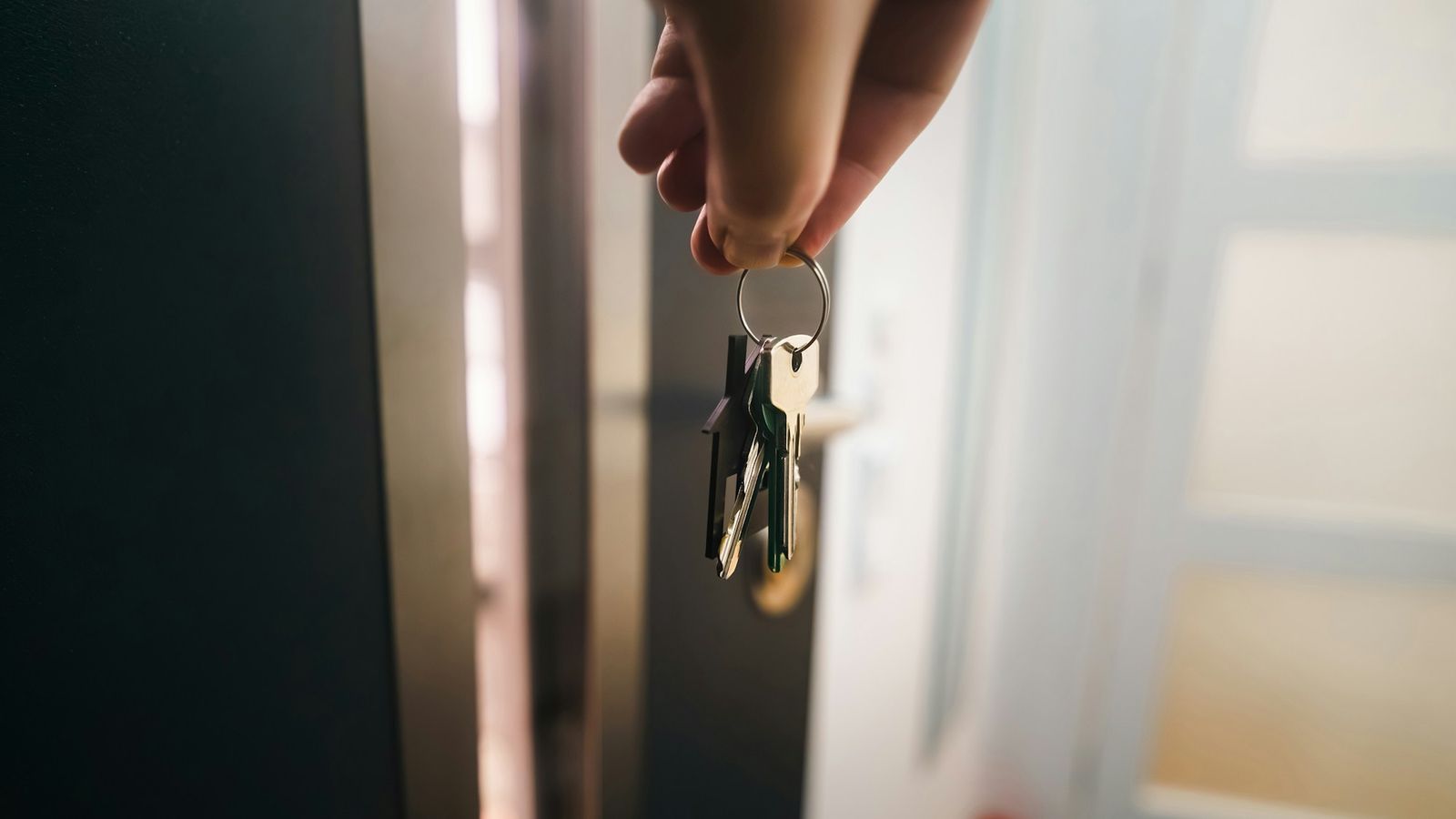 Hand holding a bunch of keys at an open apartment door