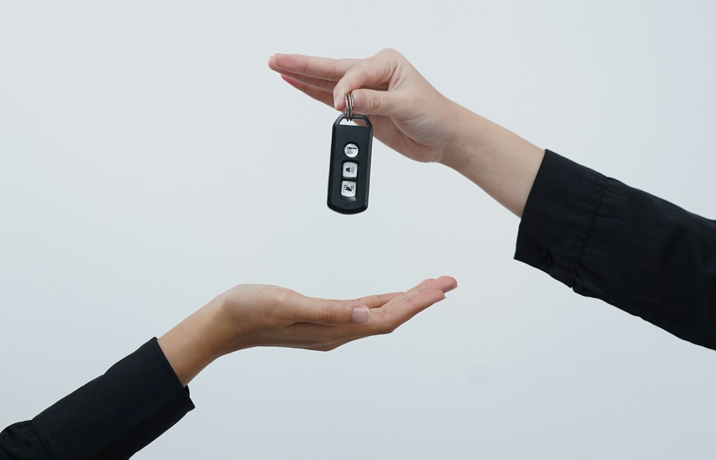 Two hands passing over a car key